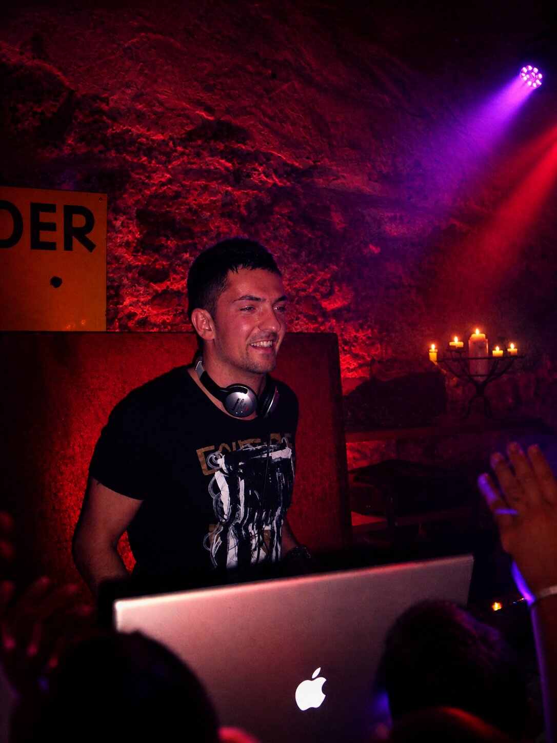 DJ Nice dans une cave voûtée éclairée en rouge, ambiance intime aux chandelles