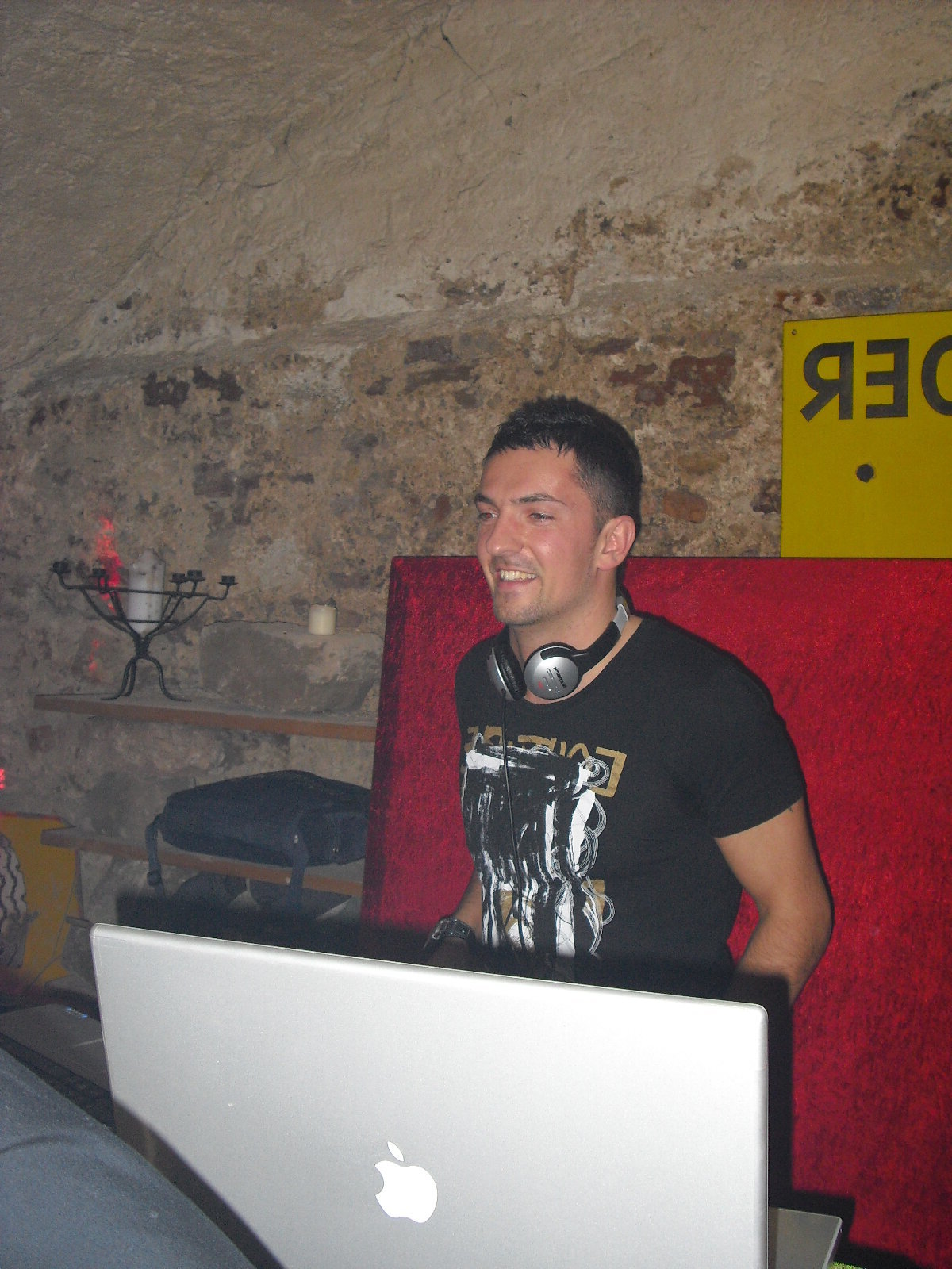 DJ Nice souriant aux platines dans une cave voûtée en pierre