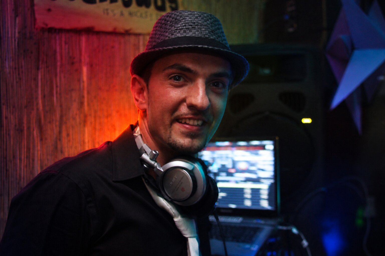 DJ Nice avec chapeau fedora et casque audio en club